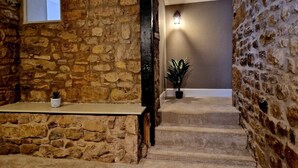 A stone-walled staircase with a small shelf and a potted plant at the bottom. - The Hamilton luxury apartments-Lord William suite (Cabus)