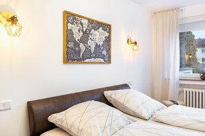 Ein Schlafzimmer mit einem Bett, Kissen, einer Weltkarte als Wandbild und Wandleuchten.