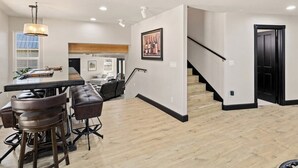 Cozinha moderna com bancada, piso de madeira e escada para outro andar.