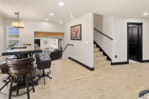 Una cocina moderna con barra, piso de madera y una escalera que sube a otro nivel.
