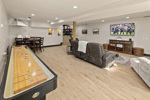 Una mesa de billar, un sofá, un televisor y una escalera en una sala de estar.