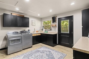Una cocina moderna con armarios negros, electrodomésticos de acero inoxidable, una ventana con vistas y una puerta negra.