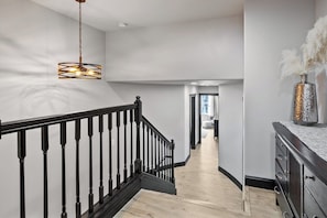 Een modern interieur met een trap, houten vloeren en een hanglamp.
