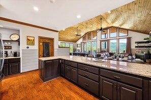 A spacious kitchen with dark cabinetry, a large island, and a wooden ceiling.