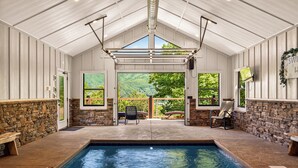 Una piscina interior con paredes de piedra, un banco y vistas a la vegetación exterior.