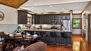Una cocina moderna con muebles oscuros, electrodomésticos de acero inoxidable y una zona de comedor de madera.