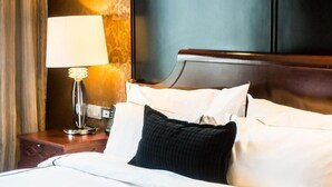 A hotel room with a neatly made bed, a bedside lamp, and a wooden nightstand. - Ostee Lodge (North Legon)