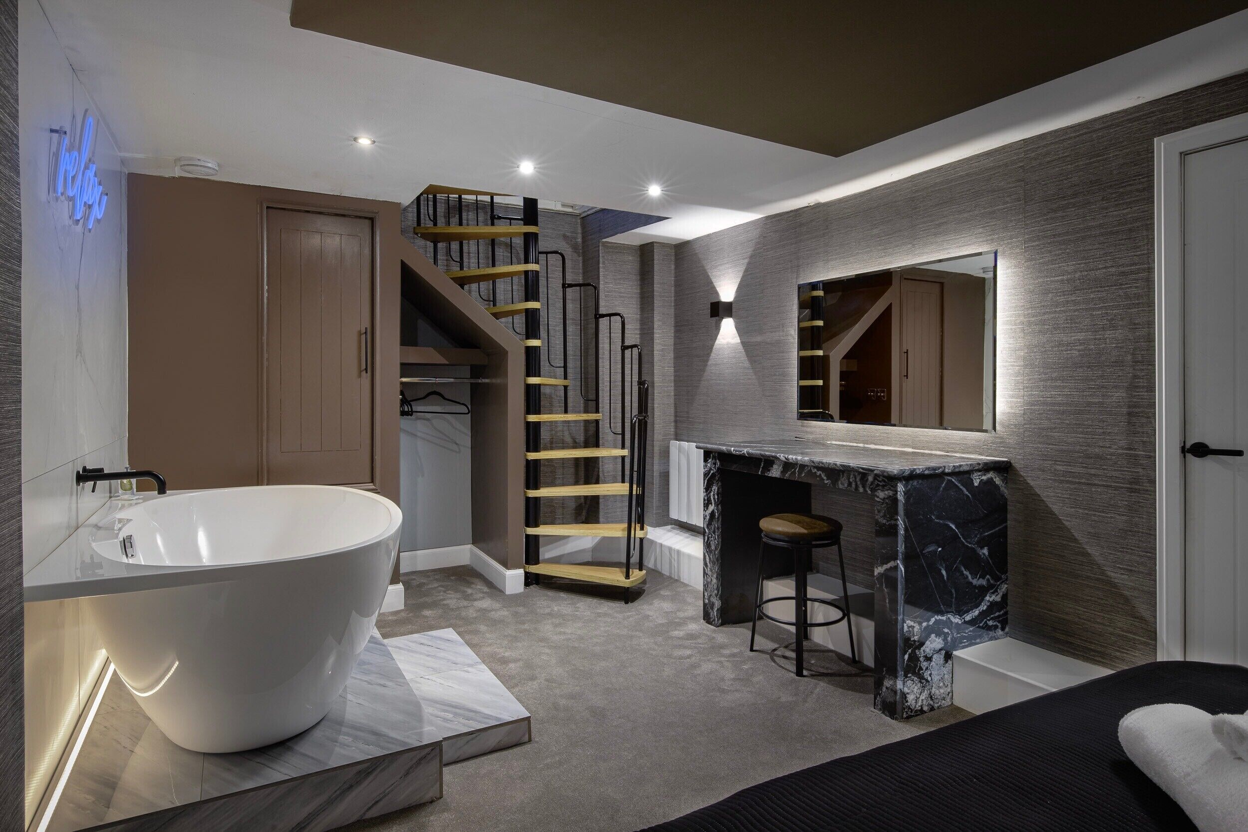 A modern bathroom with a freestanding bathtub, a marble vanity, and a wooden ladder leading to a lofted space.