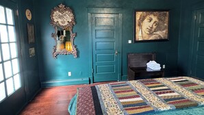 Ein schlafgemütliches Zimmer in Türkis mit einem großen Bett, einer Kommode, einem Spiegel und einem Bild an der Wand.