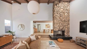 A modern living room with a stone fireplace, a sofa, a coffee table, and a TV.