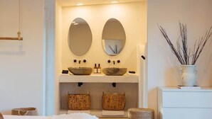 Une salle de bain avec deux miroirs ovales, un lavabo en pierre et un panier tressé posé sur le comptoir.