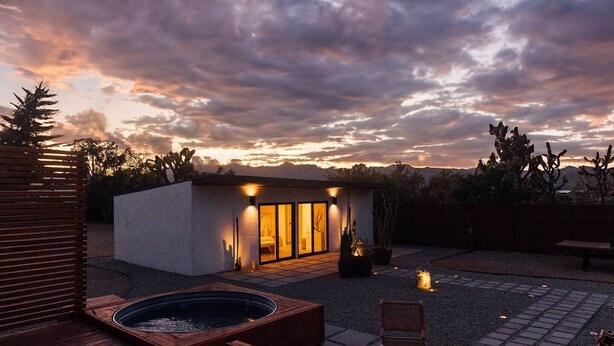 Une terrasse extérieure moderne dotée d’un jacuzzi, d’un espace salon et d’un bâtiment avec des portes vitrées.