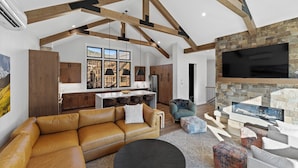 A spacious living area with a large sofa, a fireplace, and a kitchen in the background. - Ac39k4 (Keystone)
