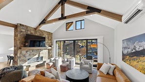 A spacious living room with a stone fireplace, leather sofas, and a large window offering a view of the outside. - Ac39k4 (Keystone)