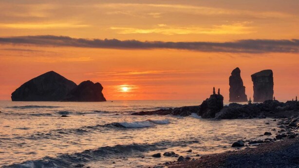 A sunset over a rocky coastline with large rock formations silhouetted against the sky. - Margarida & Miguel-Turismo e Alojamento (Ponta Delgada)