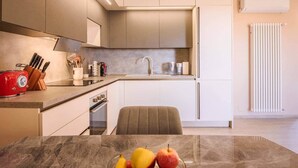 Una cocina moderna con encimera de mármol, un tostador rojo de estilo antiguo y un frutero.
