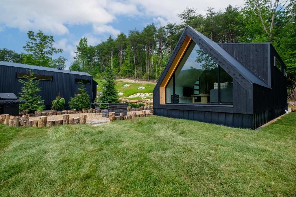 A modern cabin with a sloped roof, large windows, and a wooden deck.