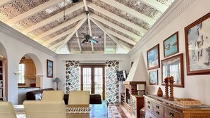 Un amplio salón con techo alto, chimenea, mesa de comedor y zona de cocina.