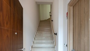 Una escalera con una puerta de madera a la izquierda y otra puerta de madera a la derecha.