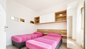 A room with two beds, a wooden headboard, a mirror, and built-in shelves. - Apartment 'Francesca, Bilo A' with Shared Terrace, Wi-Fi and Air Conditioning (Peschici)