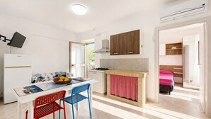 A modern kitchen with a dining area, a small dining table, chairs, and a kitchen island. - Apartment 'Francesca, Bilo A' with Shared Terrace, Wi-Fi and Air Conditioning (Peschici)