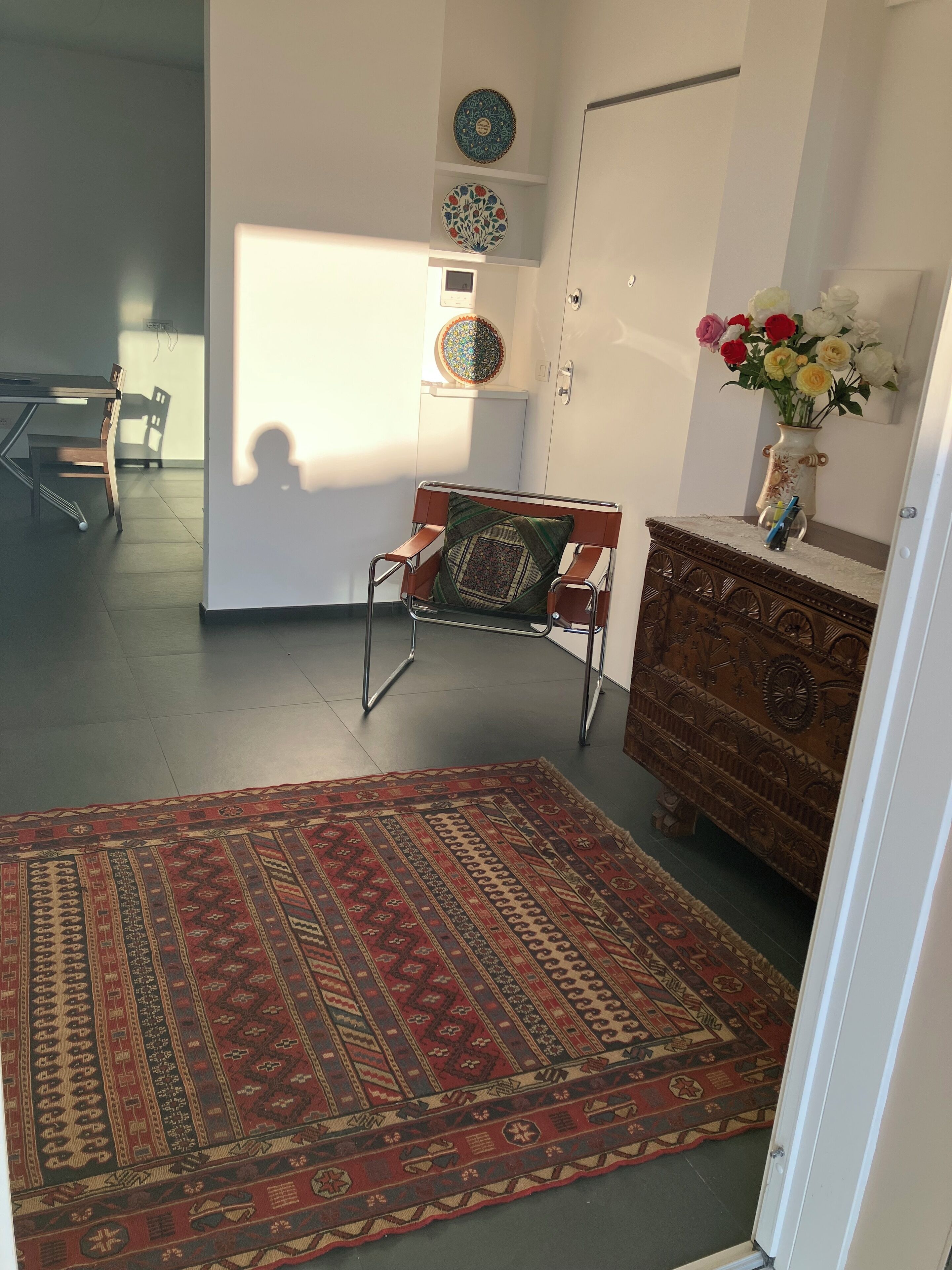 Ein Zimmer mit einem gemusterten Teppich, einem Holzschrank und einem Sessel.