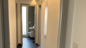 Un pasillo estrecho de diseño moderno que conduce a un baño con lavamanos y espejo.