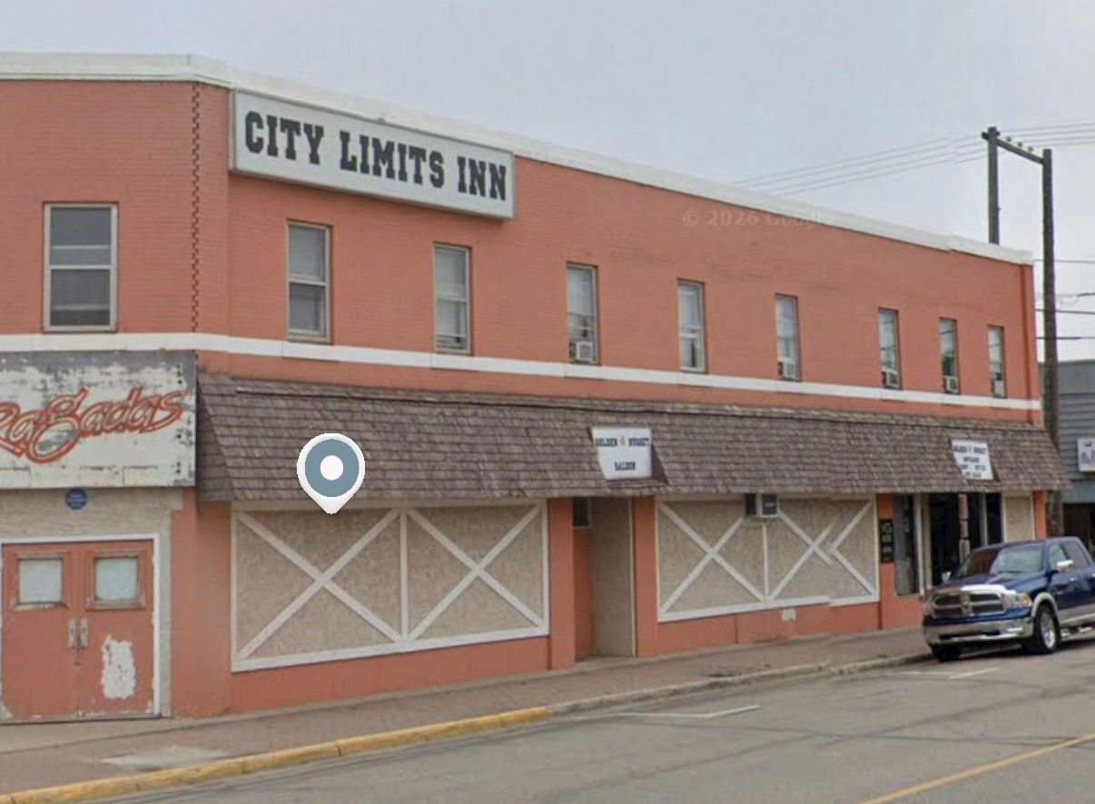 A building with a sign reading 'CITY LIMITS INN' and a parked car in front.