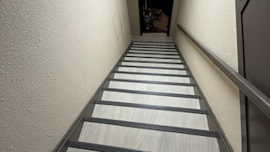 A narrow stairway with a handrail, leading to a dark doorway at the top. - City Limits Inn Hotel (Yorkton)