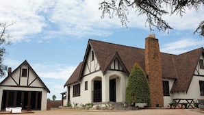 Un grand bâtiment à deux étages, doté d’une cheminée imposante, d’un petit porche et d’une allée gravillonnée.