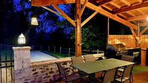 An outdoor patio with a stone wall, wooden deck, and a grill area. - Gîte "La Prèze" - Deluxe 2 Bedrooms (n°4) (Rouzède)