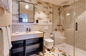 Een moderne badkamer met spiegel, wastafel, toilet en douche.