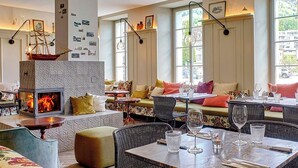 Un restaurante acogedor con chimenea, asientos cómodos y ventanas amplias.