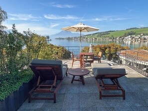 Eine Terrasse mit Sitzgelegenheiten und Blick auf einen See und Berge.
