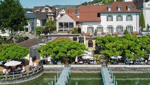Vista al río con un muelle, edificios y zonas de estar al aire libre.