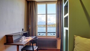 Una habitación con vista al mar, una mesa con una silla y una ventana con cortinas.