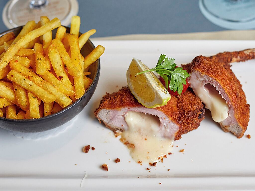 A plate with breaded and fried cutlets, a side of seasoned fries, and a garnish of parsley and lemon.