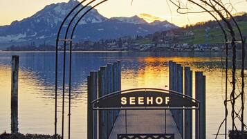 Une porte en métal portant l’inscription « SEEHOF », devant un lac, avec des montagnes en arrière-plan.