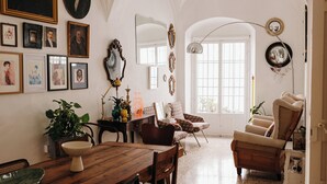 A dining area with a wooden table and chairs, a potted plant, and framed pictures on the wall. - Botánico Casa Rural (Arcos de la Frontera)