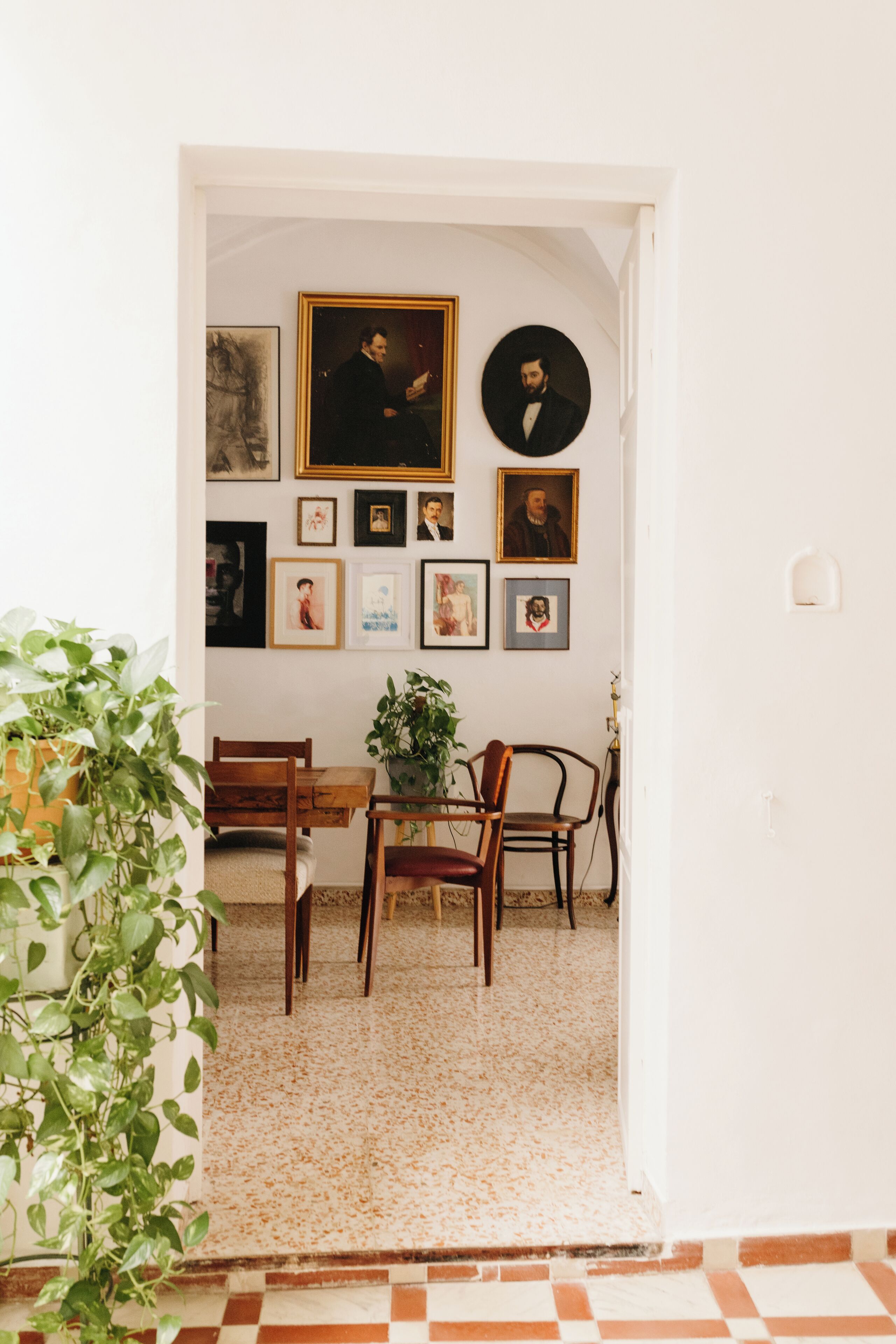 A dining area with a wooden table and chairs, surrounded by framed pictures on the wall.