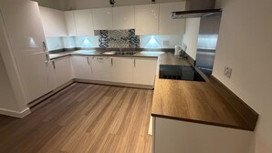 Une cuisine moderne avec des armoires blanches, un plan de travail en bois et un revêtement mural décoratif à motifs géométriques.
