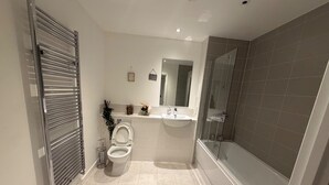 Une salle de bain moderne équipée de toilettes, d’un lavabo et d’une douche.