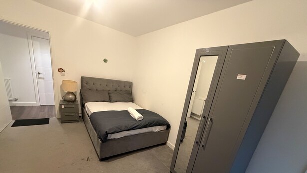 Une chambre à coucher avec un lit, une armoire, une table de chevet et une lampe.