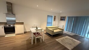 Un salon moderne comprenant une table à manger, un canapé et un coin cuisine équipé d’un four et d’une cuisinière.