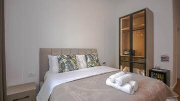 Una habitación de hotel con una cama, un armario, un letrero de 'No Fumar' y una mesita de noche con lámpara.