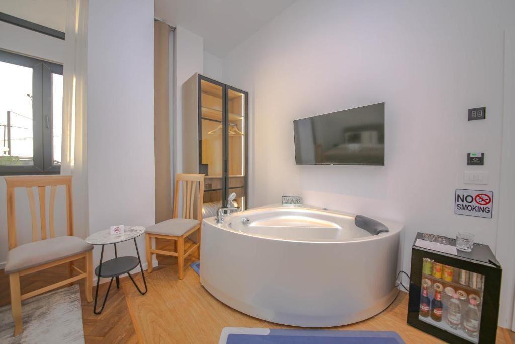 A modern bathroom with a freestanding bathtub, a mirror, a television, and a 'No Smoking' sign.