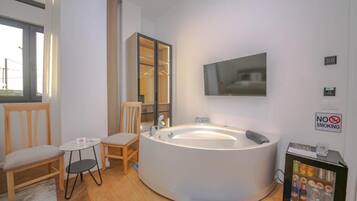 A modern bathroom with a freestanding bathtub, a mirror, a television, and a 'No Smoking' sign.