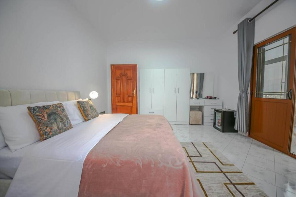 A bedroom with a bed, a wardrobe, a desk, and a bathroom.