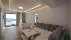A modern living room with a sofa, a coffee table, and a view of the outdoors. - Murati Lake View Hotel (Farkë)