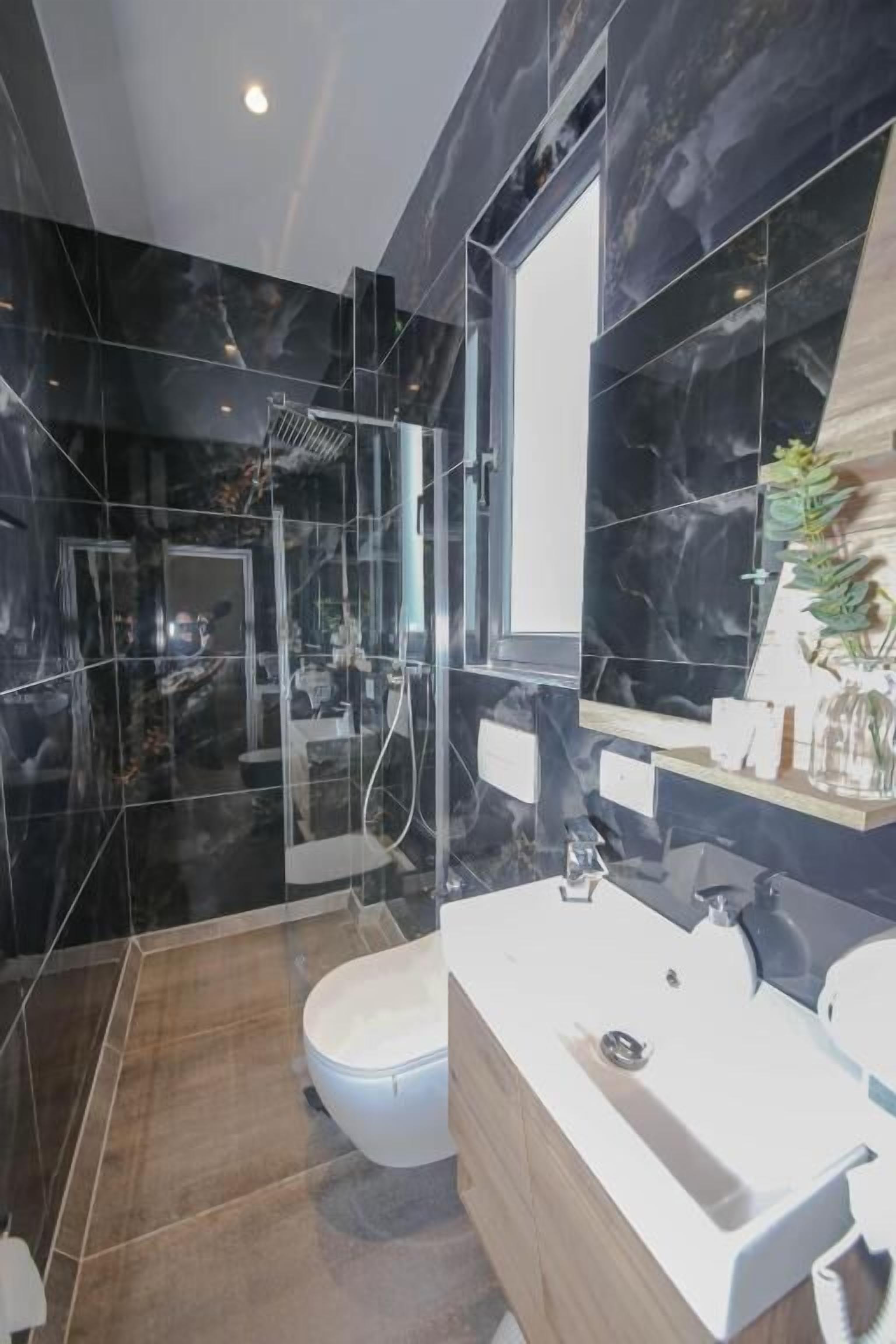 A modern bathroom with a glass-enclosed shower, a white sink, and a large mirror.
